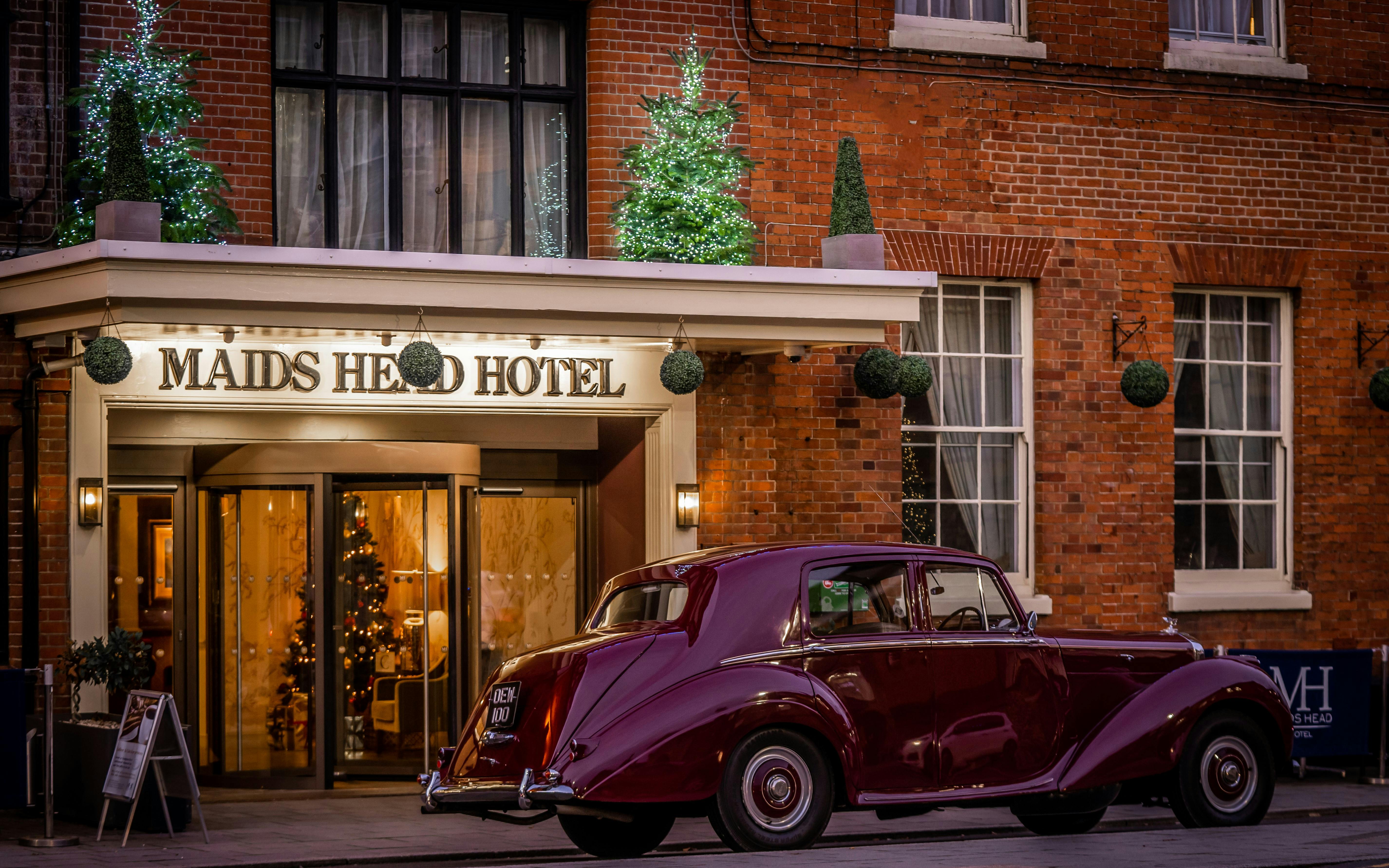 A purple Bentley parked outside a hotel.