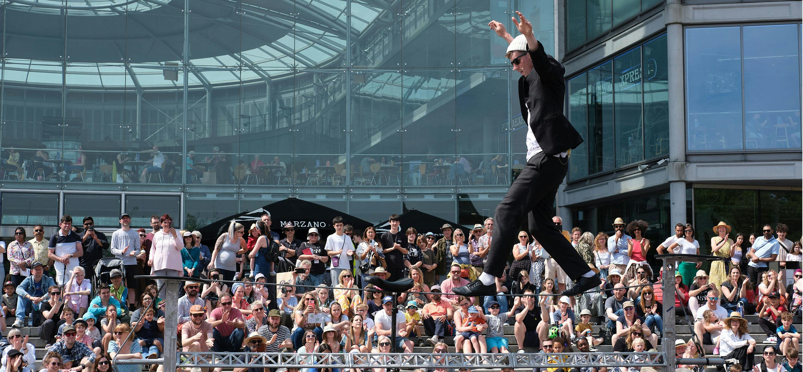 A tightrope walker performs outside The Forum in Norwich in front of a big crowd.