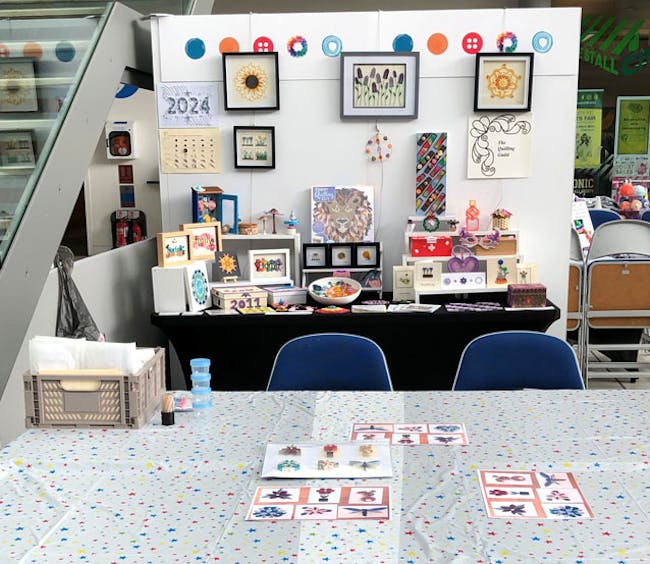 A display of colourful quilling designs and activity table.