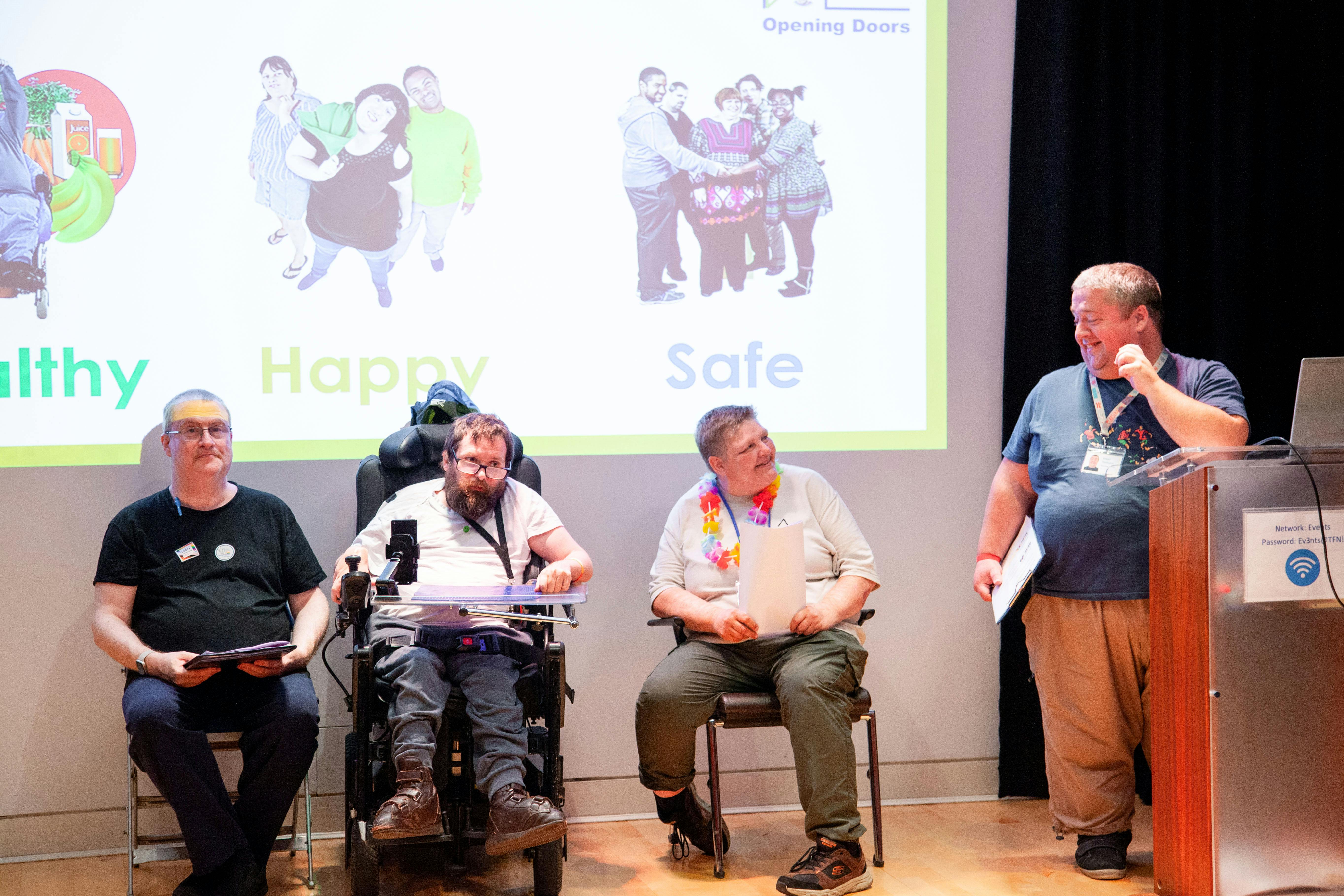 Four men presenting on stage.