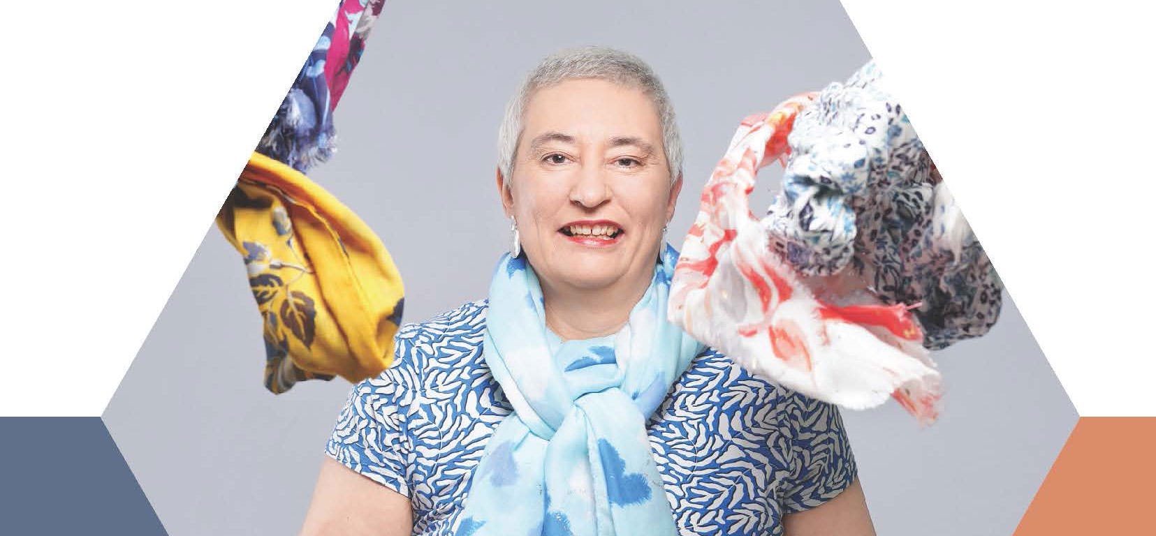 A lady with short cropped hair throws colorful head scarfs in the air.