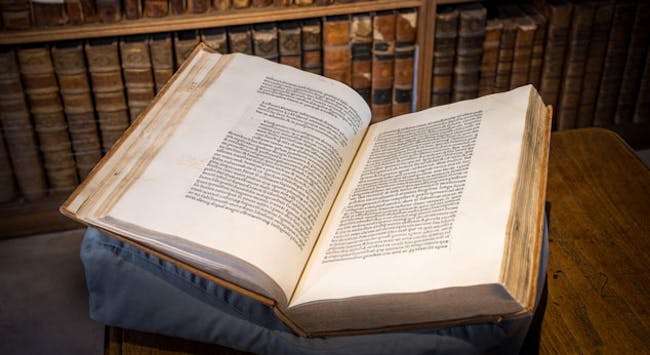 An old book open on a conservation cushion in an old library.