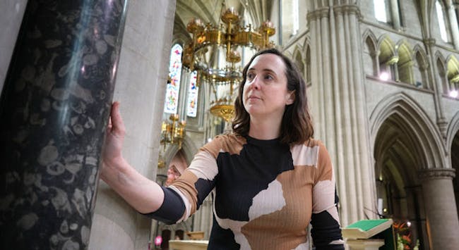 A lady looks at a patterned marble column in St John Baptist Cathedral