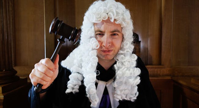 A man dressed up as a judge with a wig and gavel