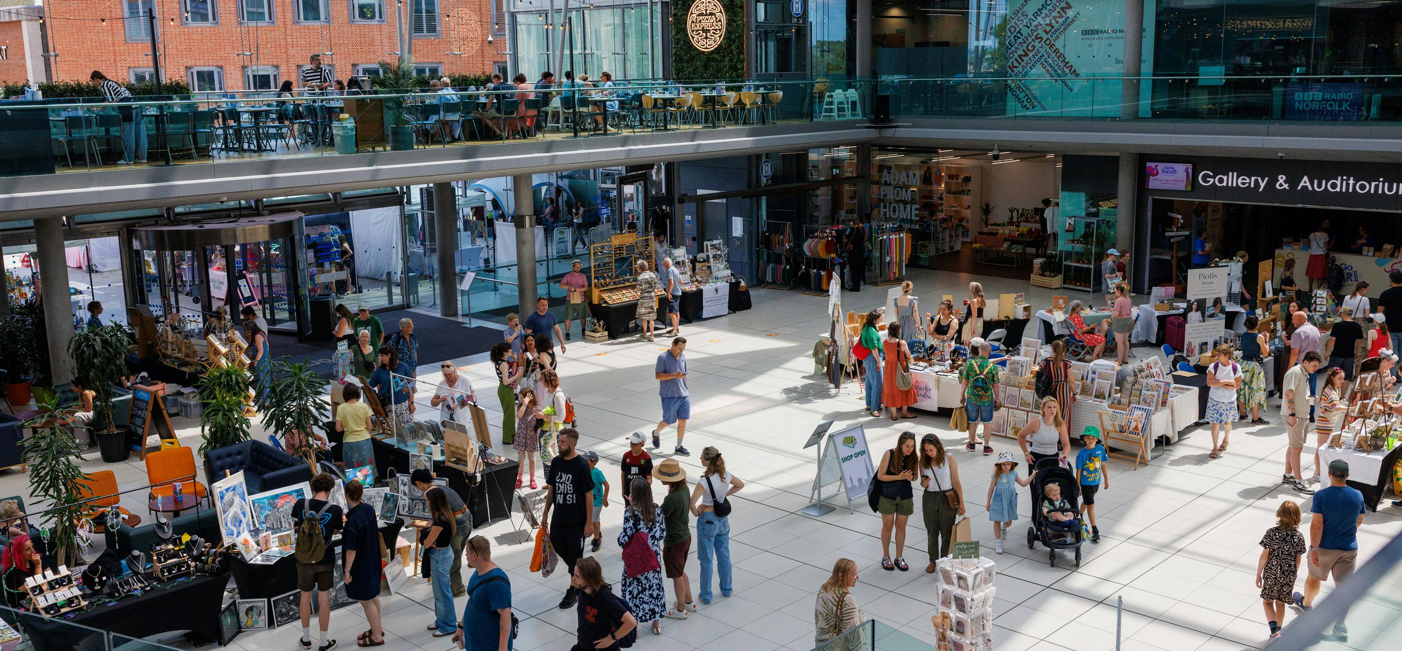 Lots of people in exploring a bright, modern space with a craft market