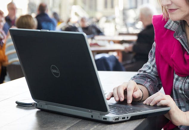 A lady in a bright scarf types on a laptop