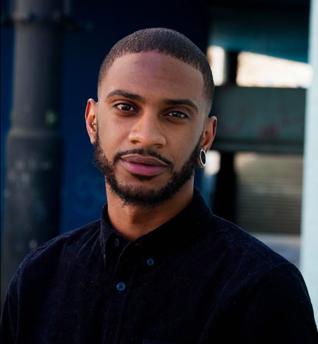 A headshot image of Ashley Hickson-Lovence, a young black man
