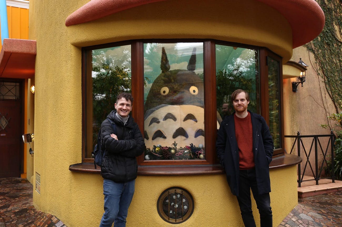Authors standing in front of museum entrance featuring a large model Totoro figure