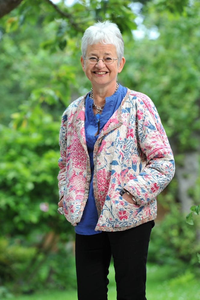 Author Jacqueline Wilson smiling into camera, wearing a quilted pink and white jacket.