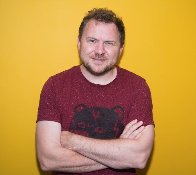 Poet Mark Grist standing with arms crossed.
