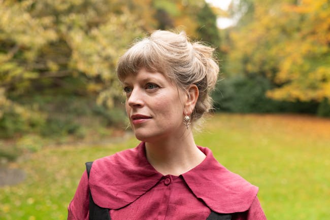 Sarah Perry, a blonde haired woman, standing in a garden setting