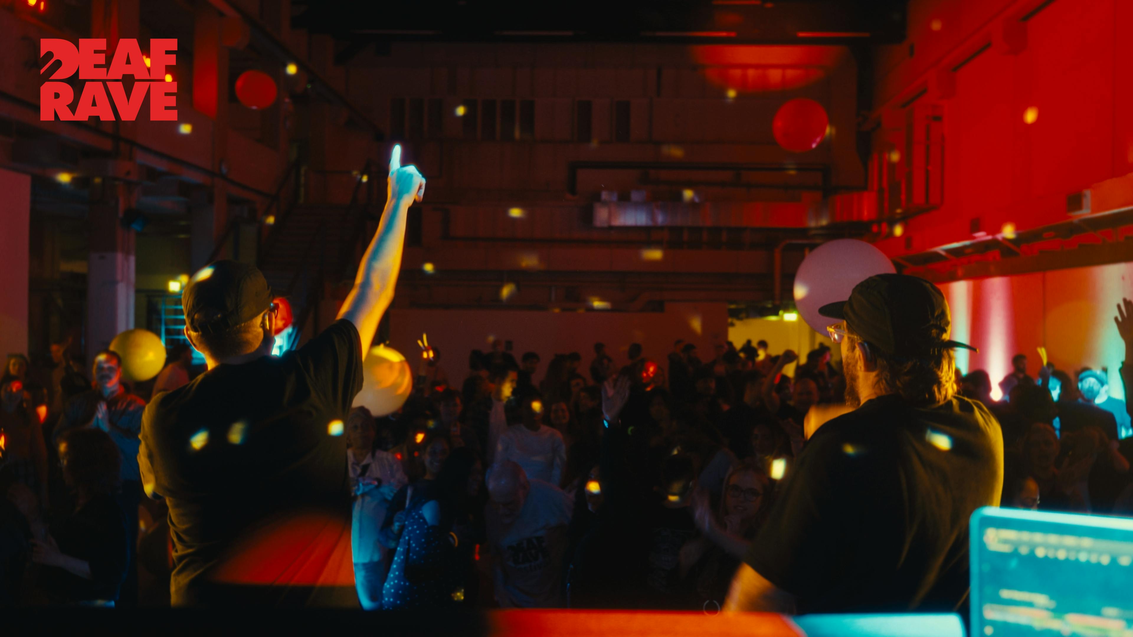 Two DJs facing an an audience at a nightclub.