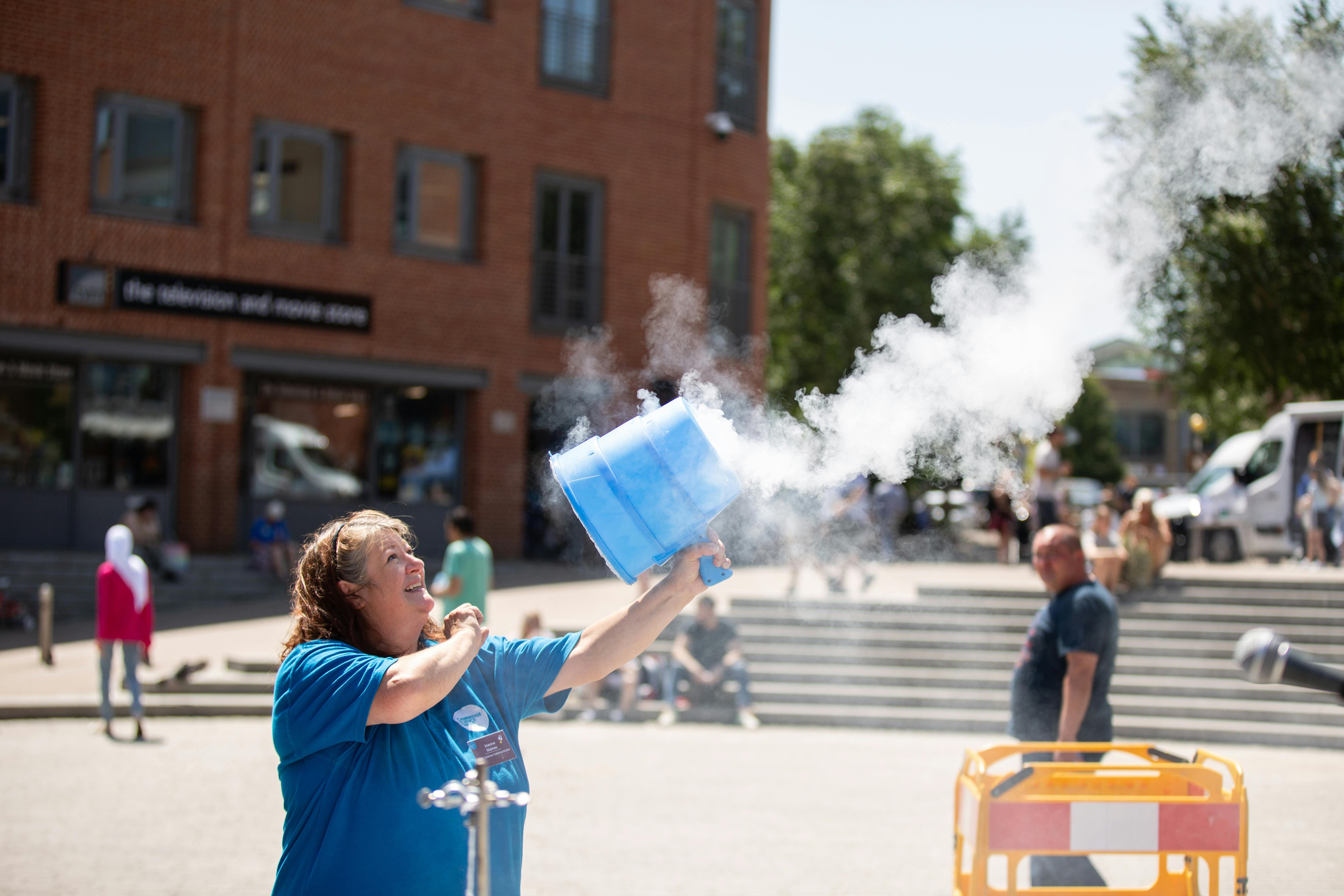 A woman with brown hair blowing smoke out of an air vortex cannon.