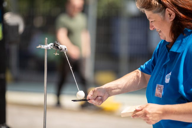 A woman balancing a ping pong ball on a tuning fork.