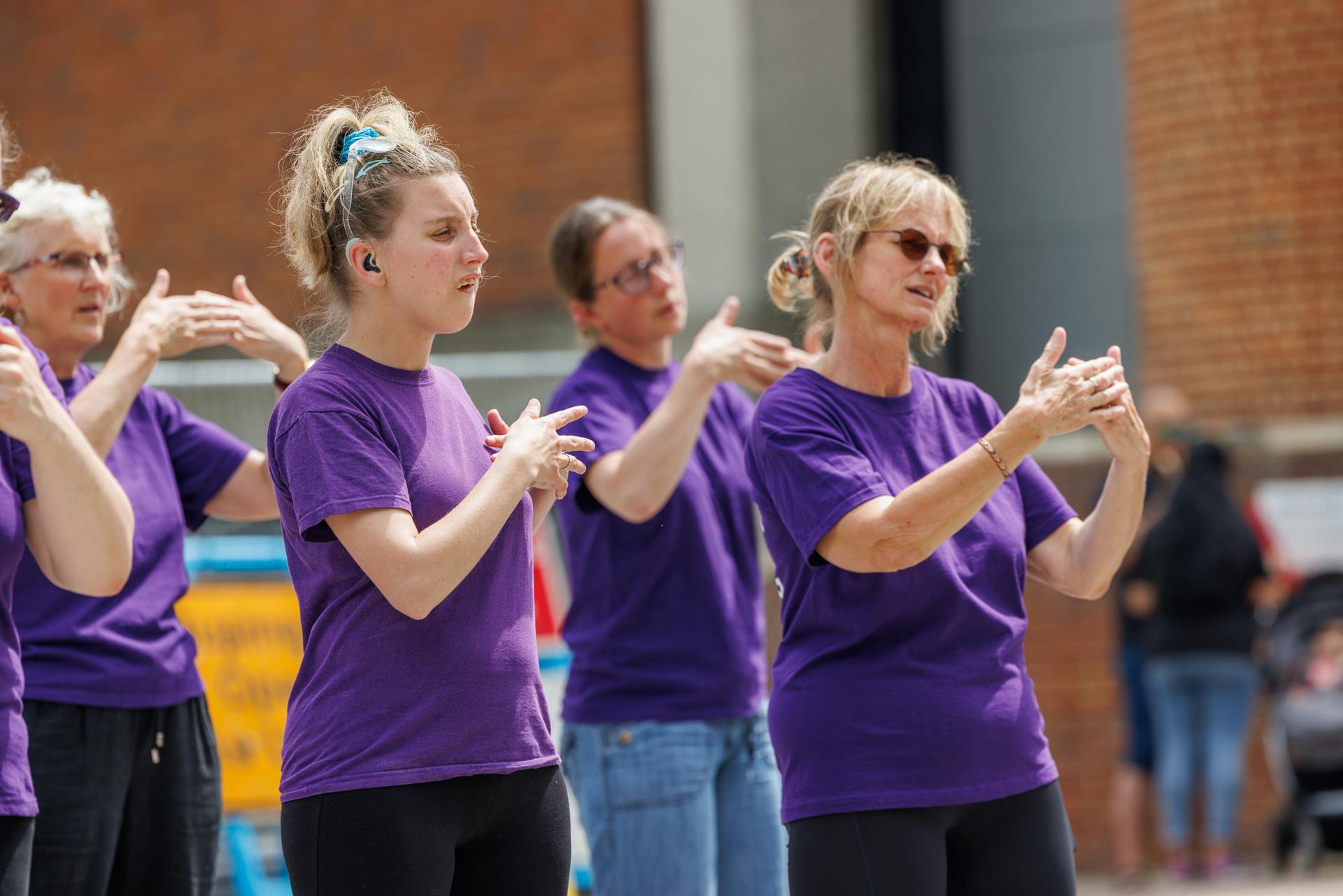 A group of women in purple t shirts signing.