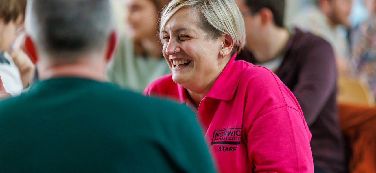 Ellie, mid-laughter, wearing a hot pink Norwich Games Festival t-shirt