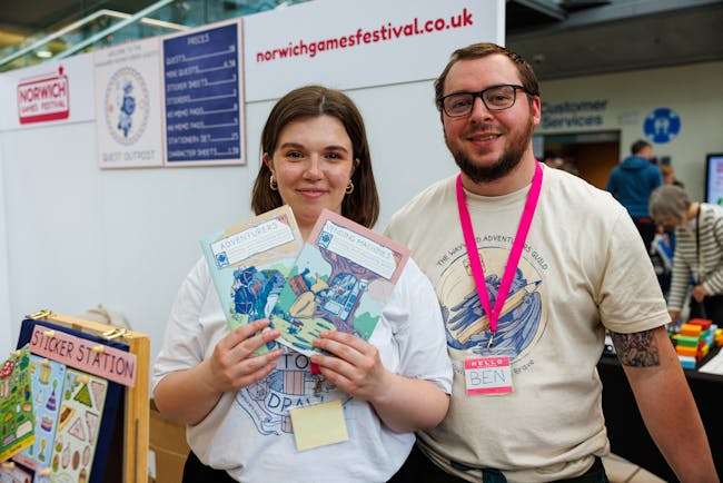 A smiling man and woman at a Norwich Games Festival stall.
