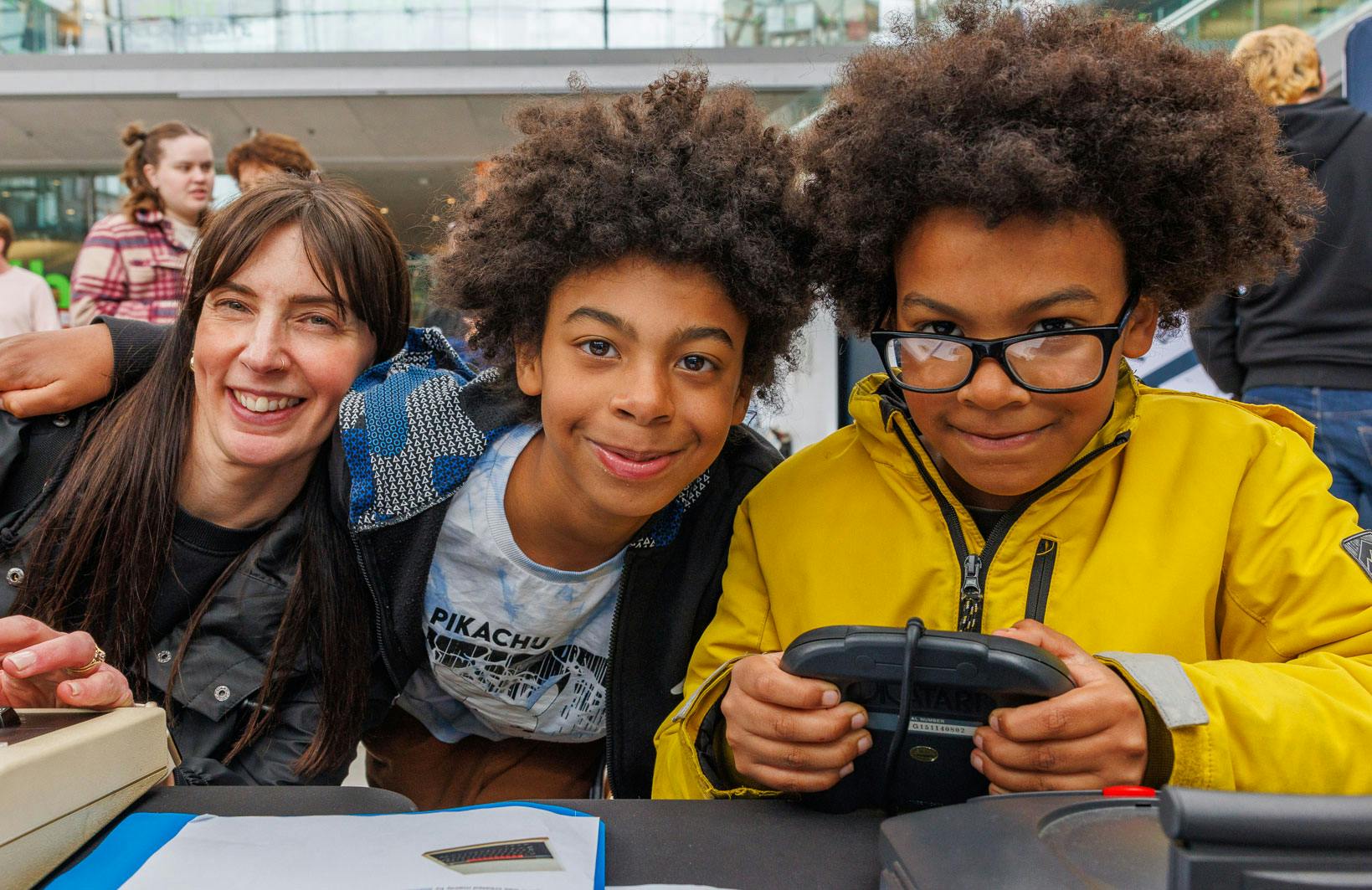 A family smile at the camera holding retro video console controllers