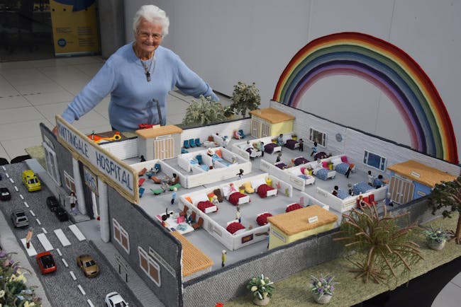 Woman standing behind knitted hospital scene