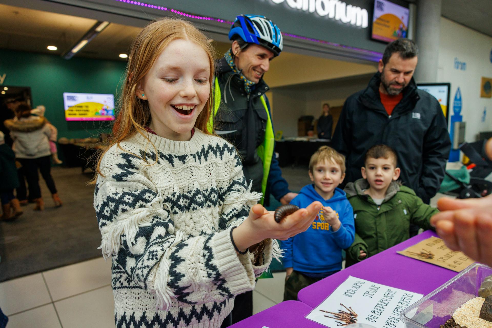 A visitor to the Festival holds a centipede in her hand and looks on in surprise.