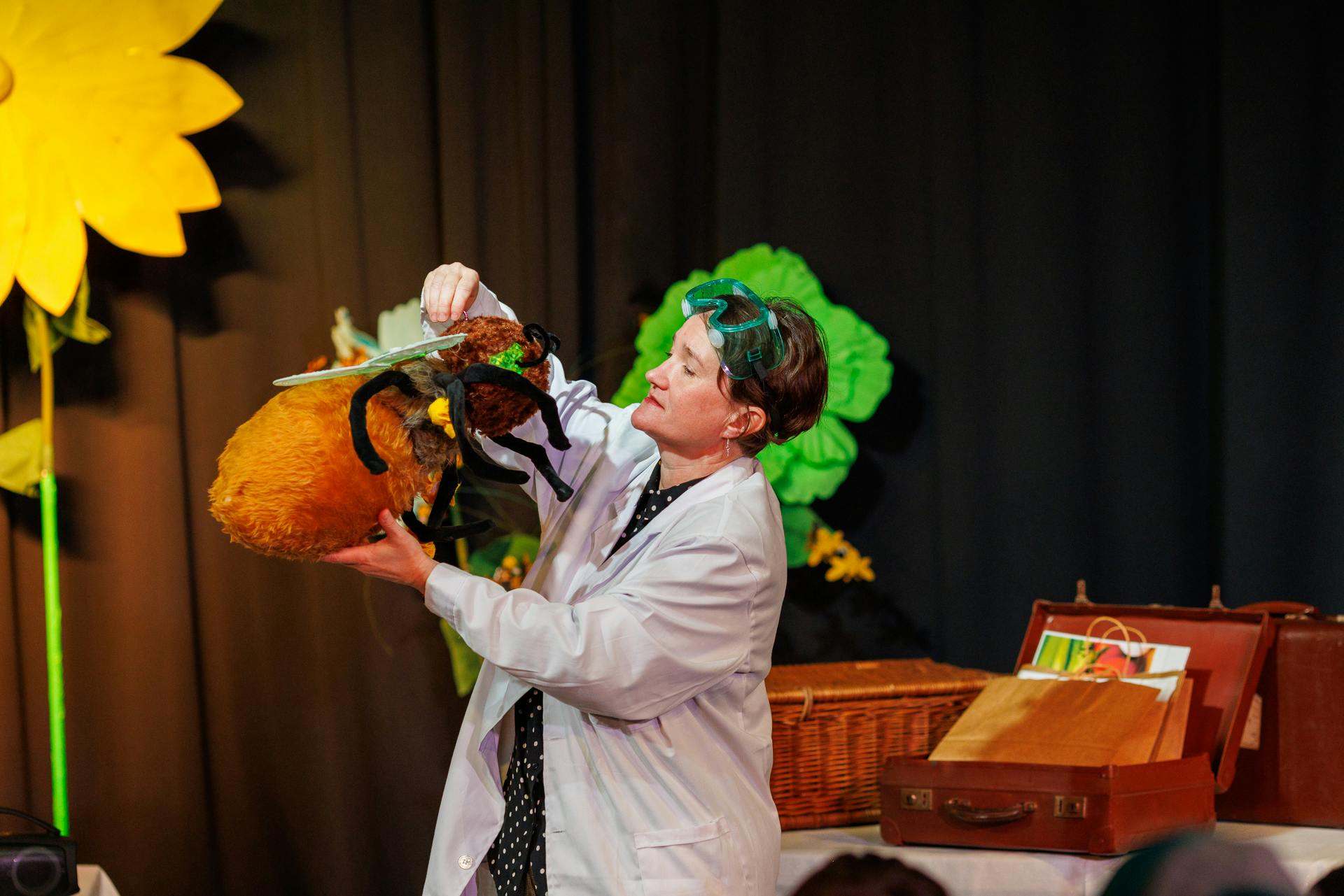An actor wearing a lab coat is on stage during a performance at Norwich Science Festival.