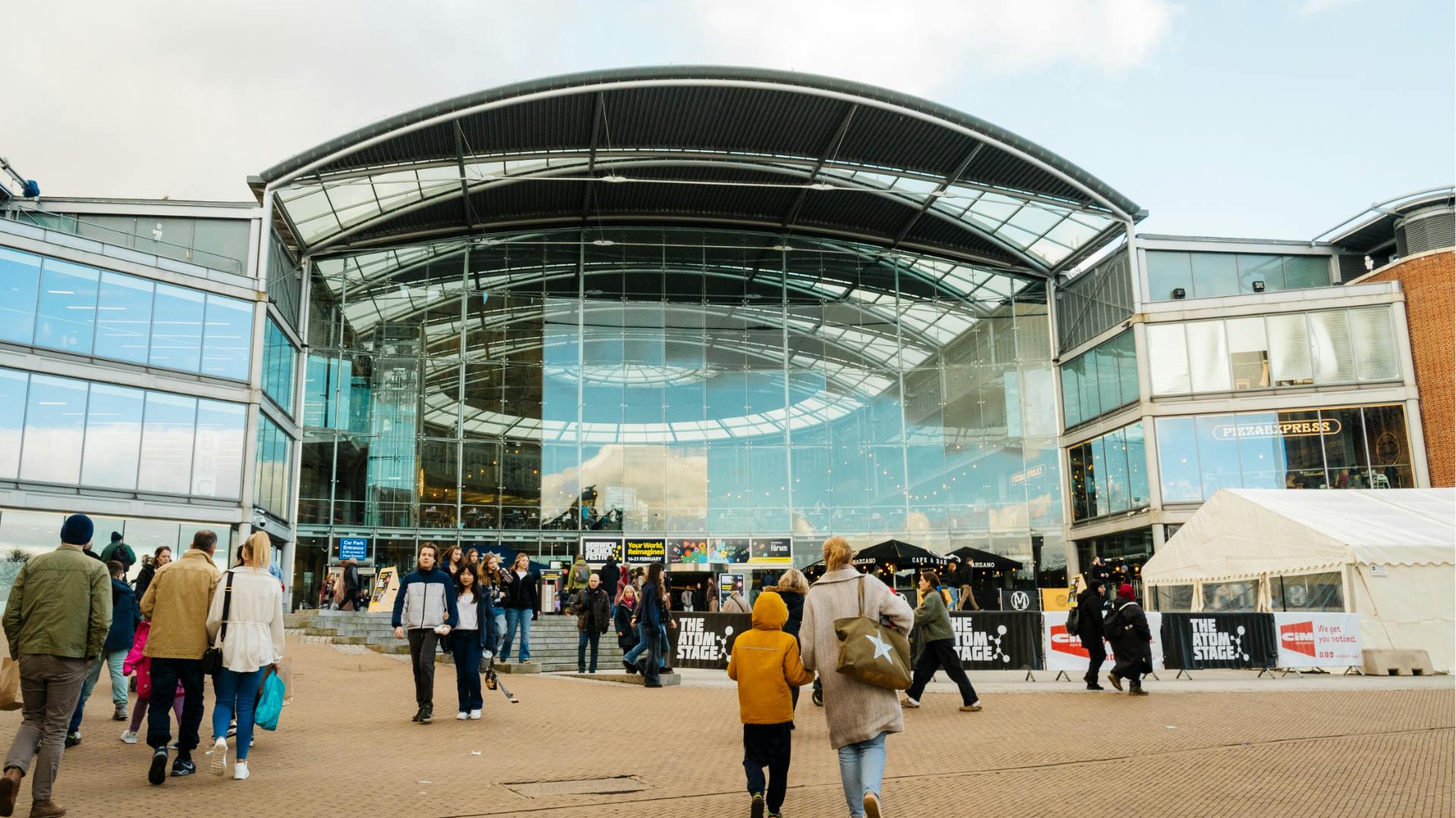 A shot of The Forum building during Norwich Science Festival, with visitors walking towards the building
