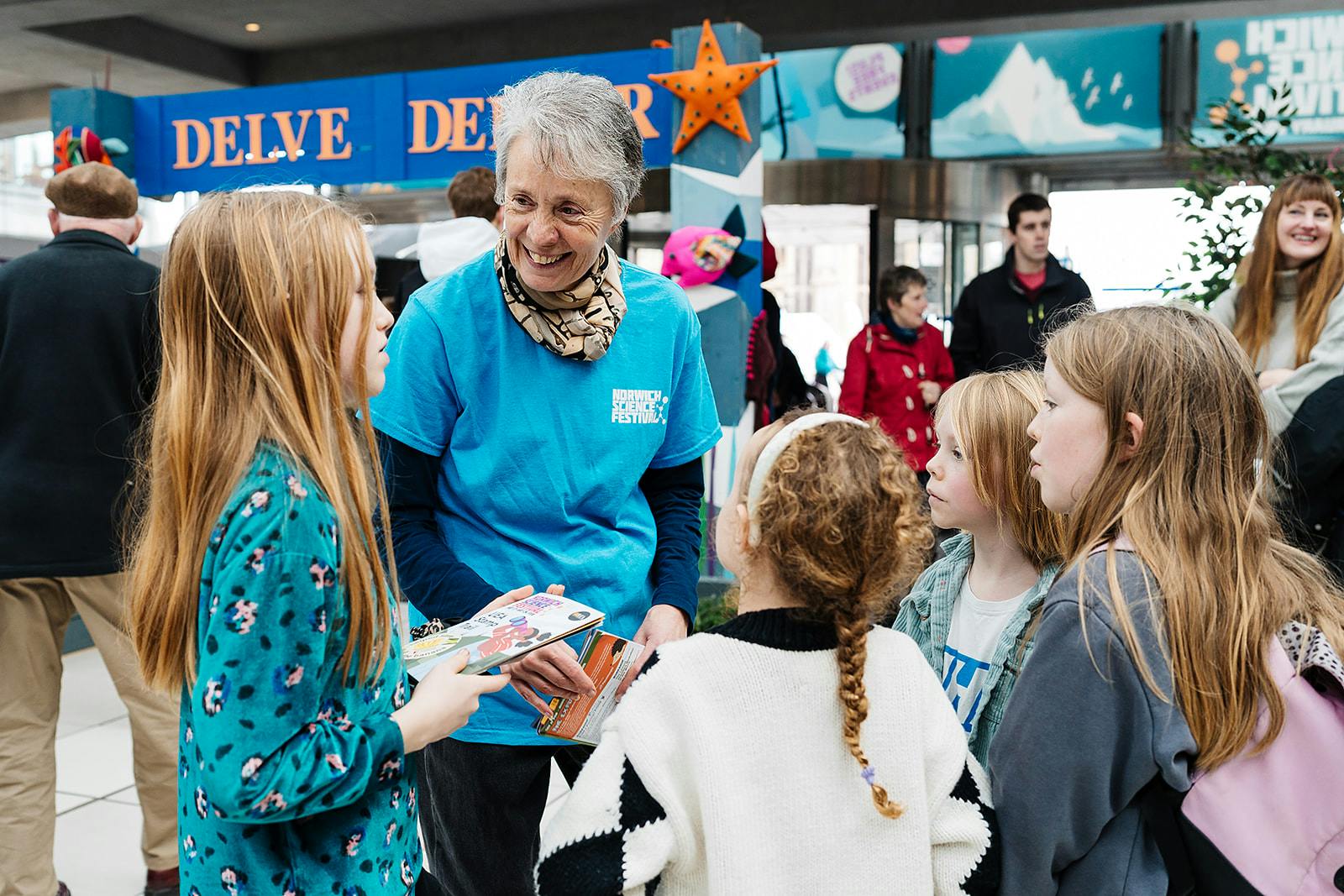 A Festival volunteer in a blue t-shirt chats to visitors in The Explorium.