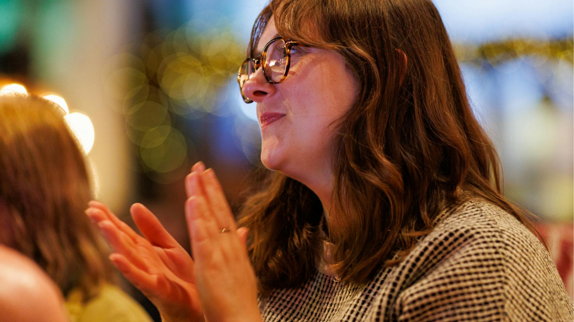 audience-member-clapping.png An audience member claps and smiles a an event.