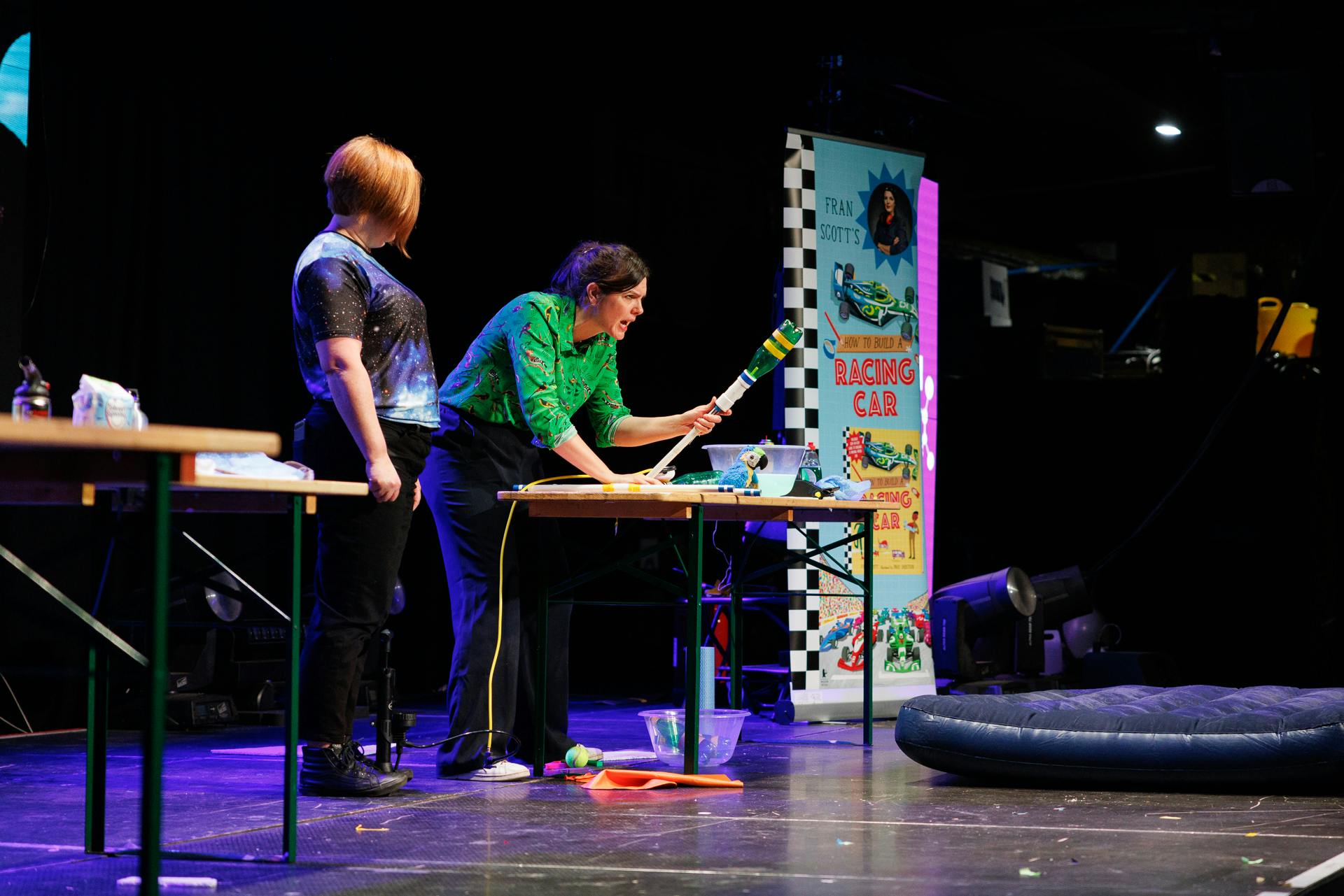 Two people on stage fire a rocket into the audience