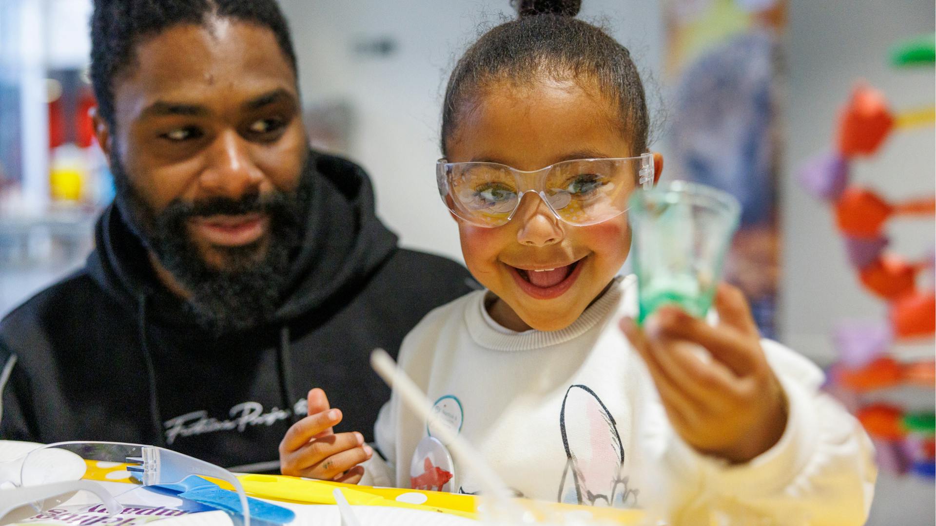 A parent and child smile as the take part in an experiment
