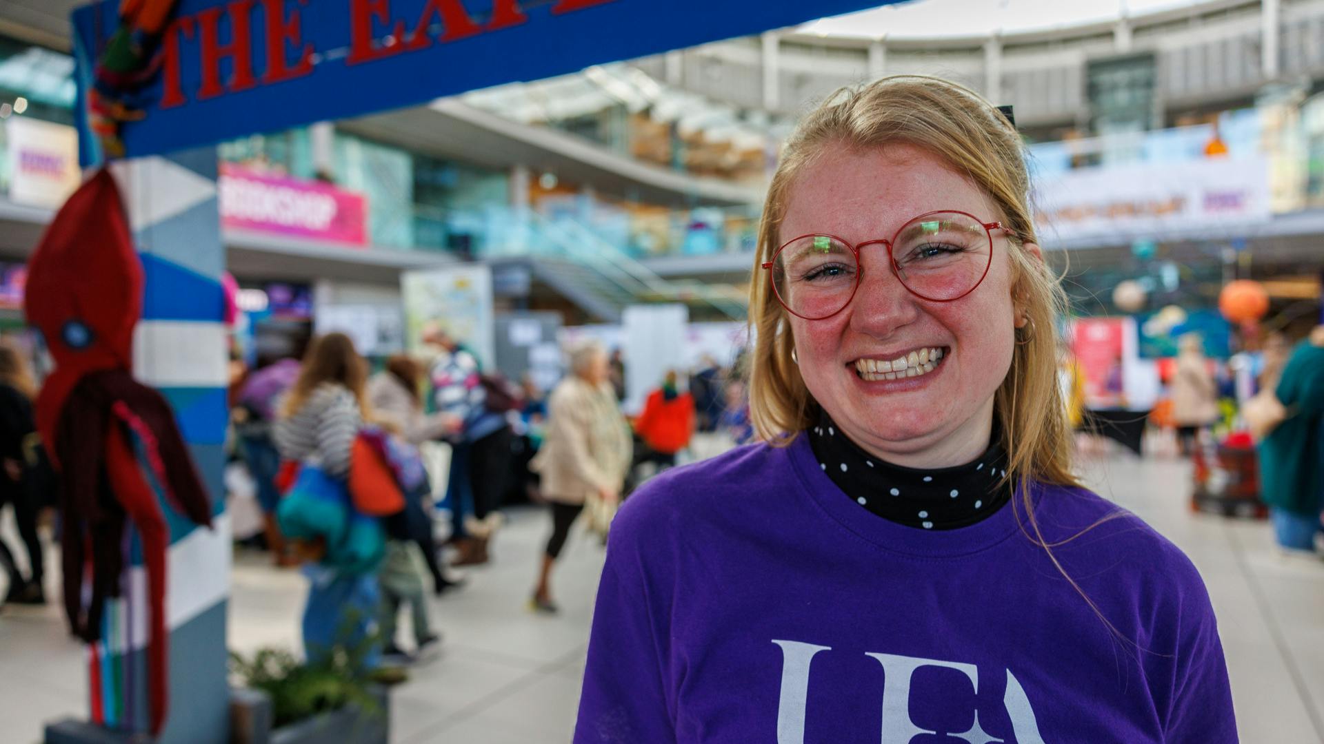 A member of UEA staff wears a purple t-shirt and smiles at the camera during Norwich Science Festival 2024