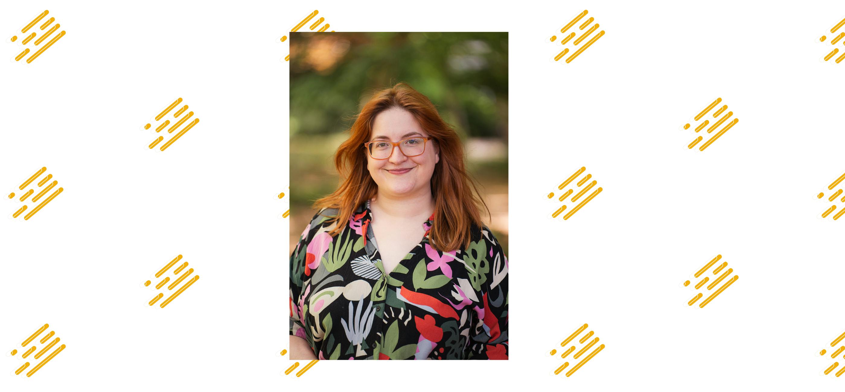 A headshot of Luisa Smith, who has red hair and wears glasses.