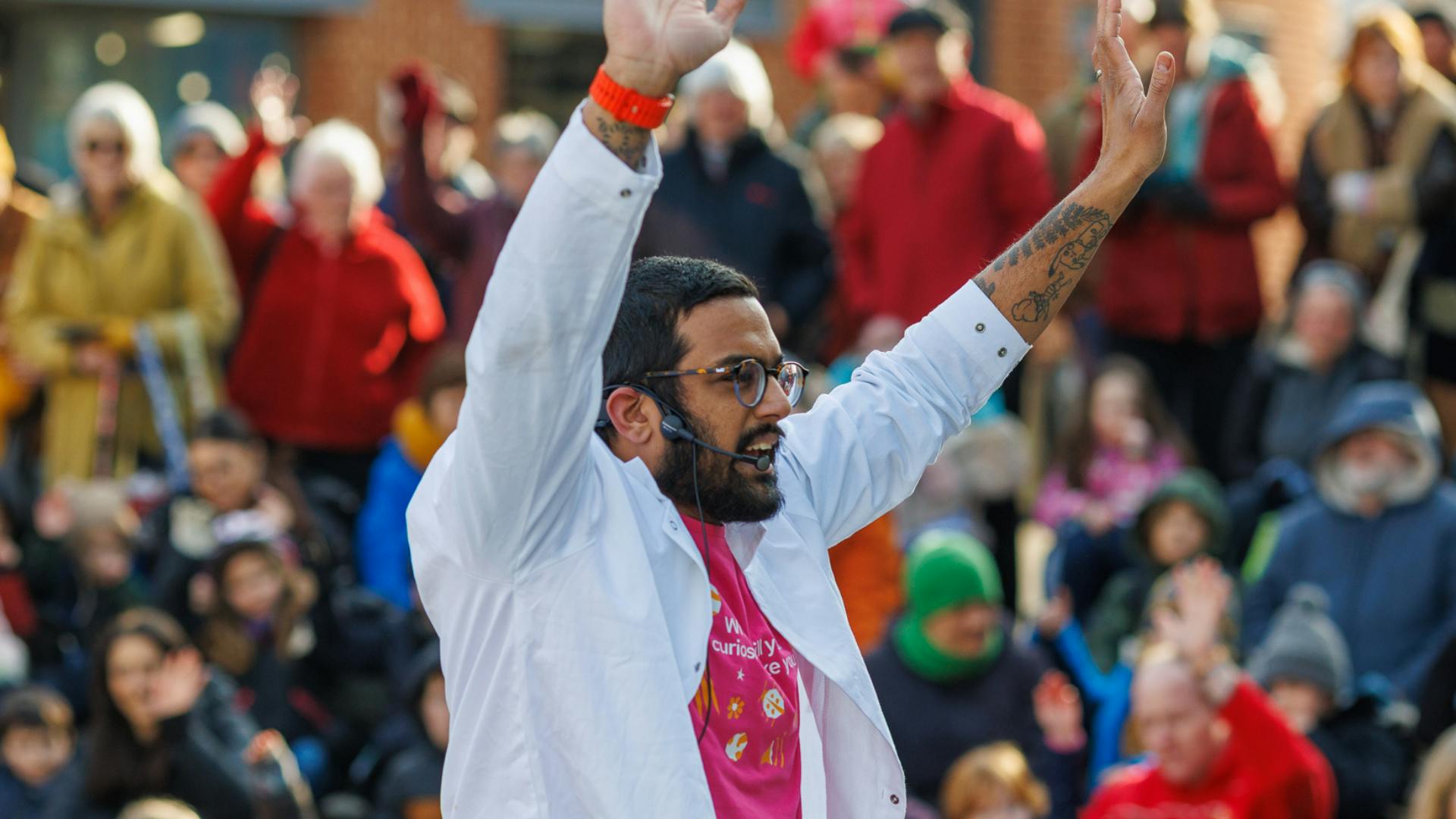 Dr Nikhil Mistry in a white lab coat with his arm in the air.