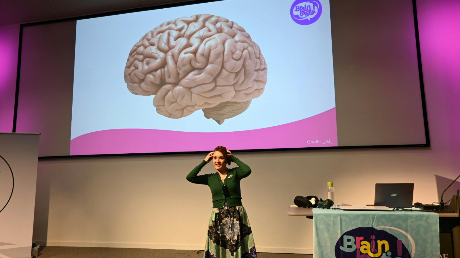 Speaker performing on stage in front of a giant projected brain.