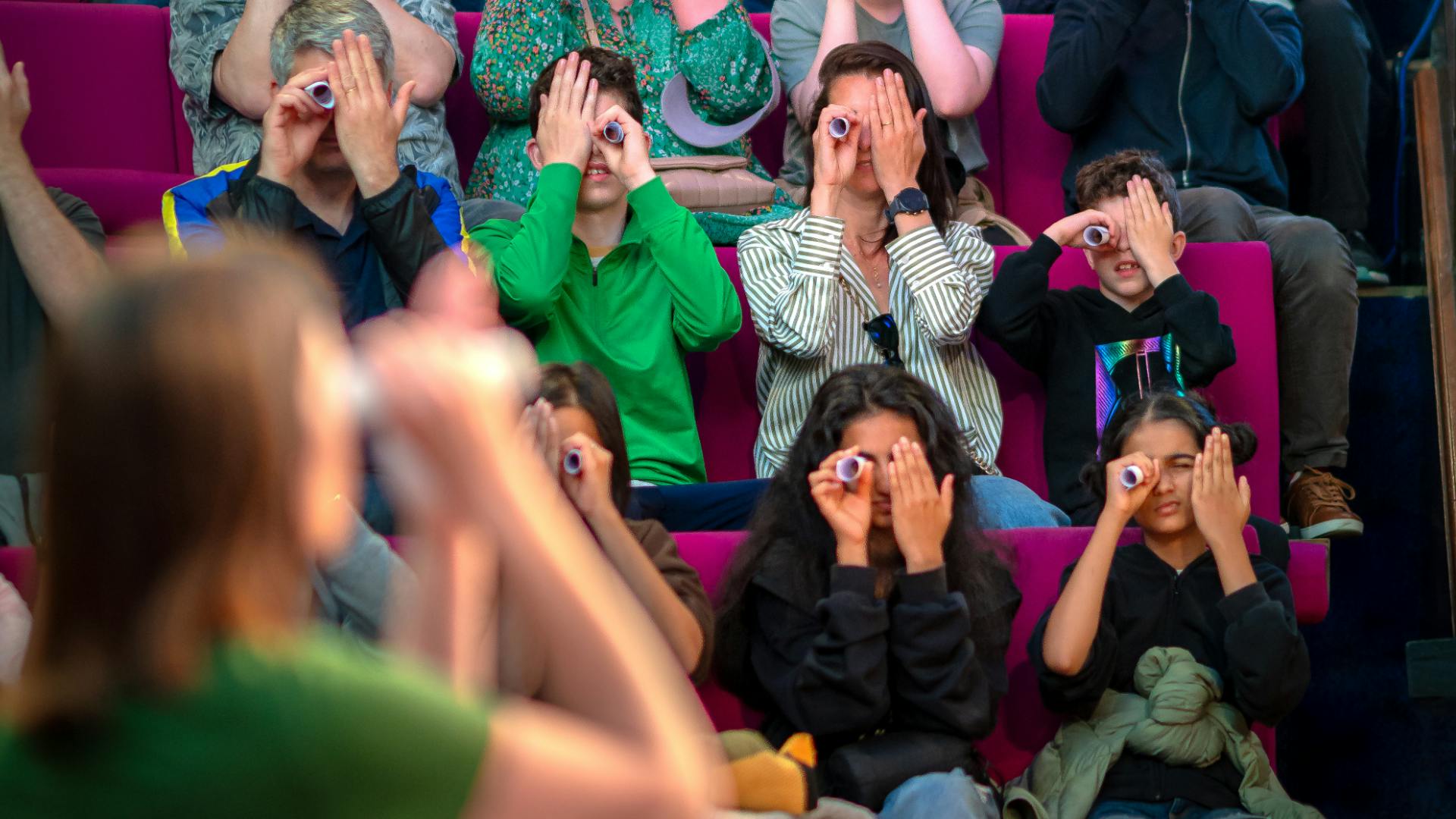 web-illusion-confusion.png An audience holding small tubes up to their eyes.