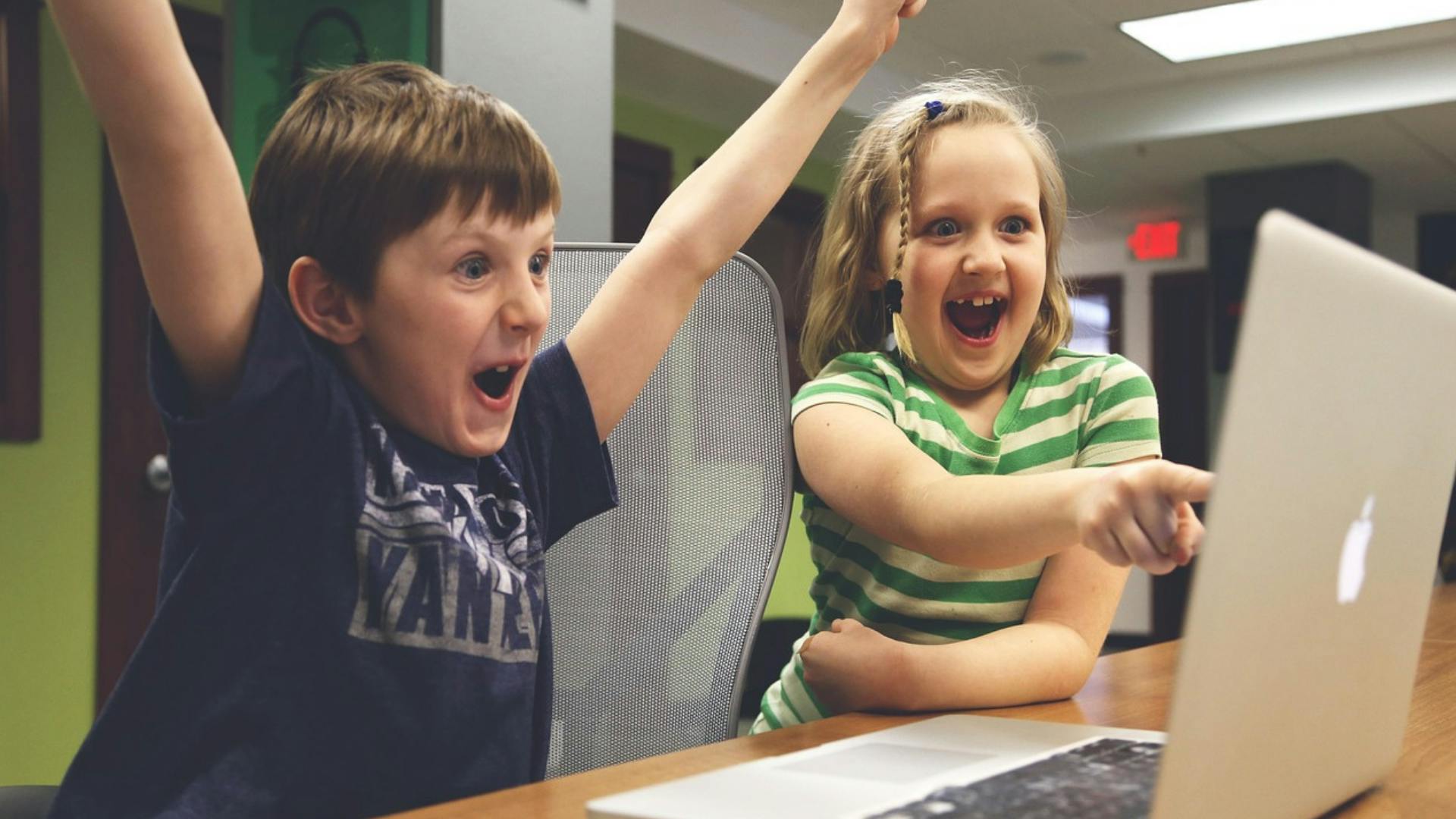 web-little-clicks,-big-ideas.png Two children celebrating something on a laptop screen.