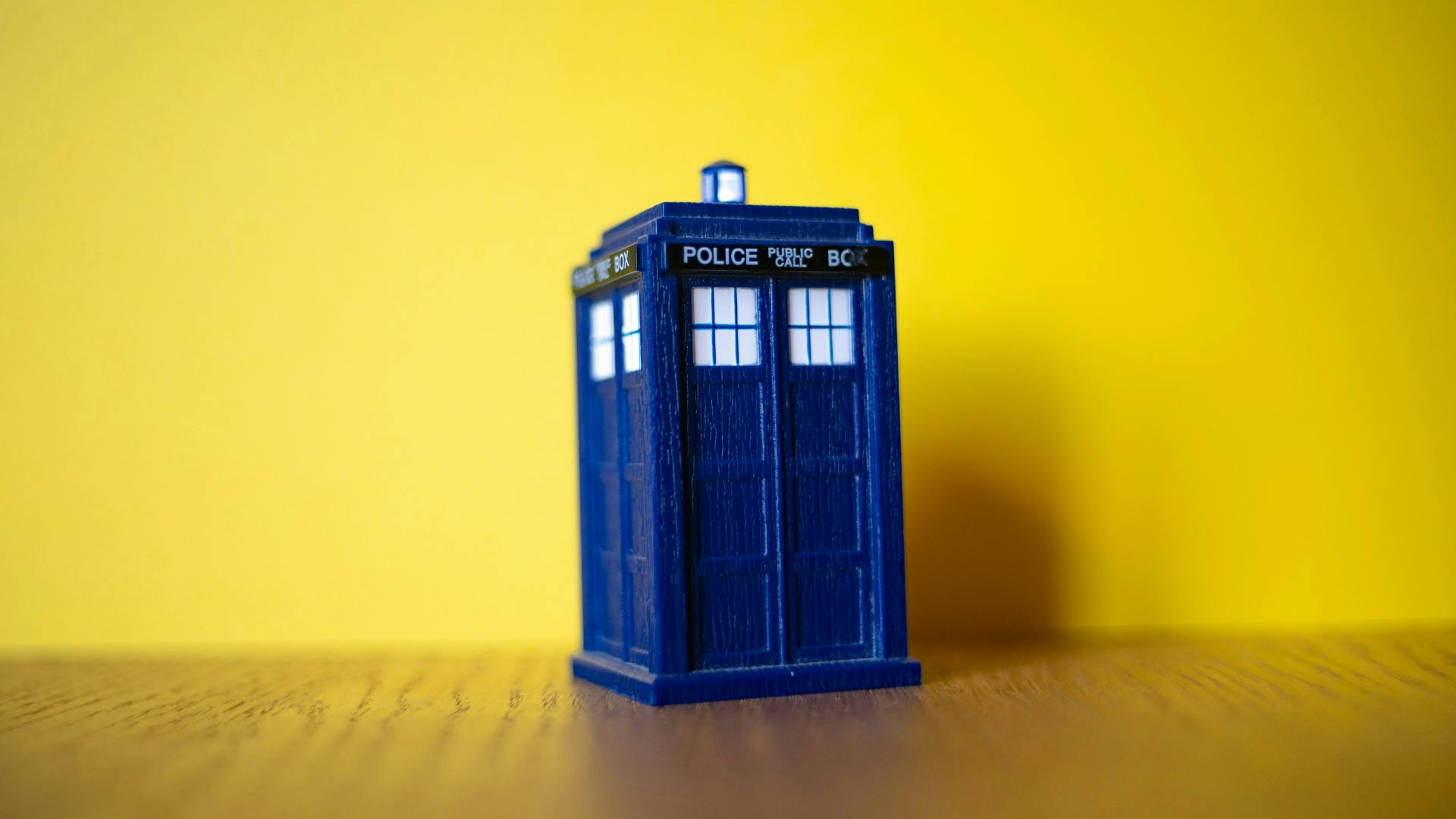 web-time-and-space.png A TARDIS against a yellow backdrop.