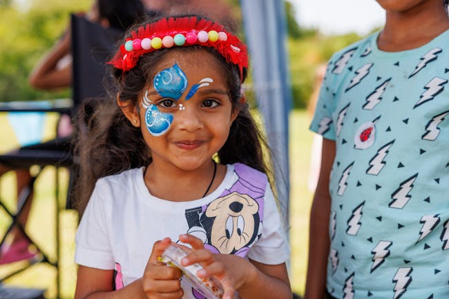 A child with her face painted with a blue butterfly