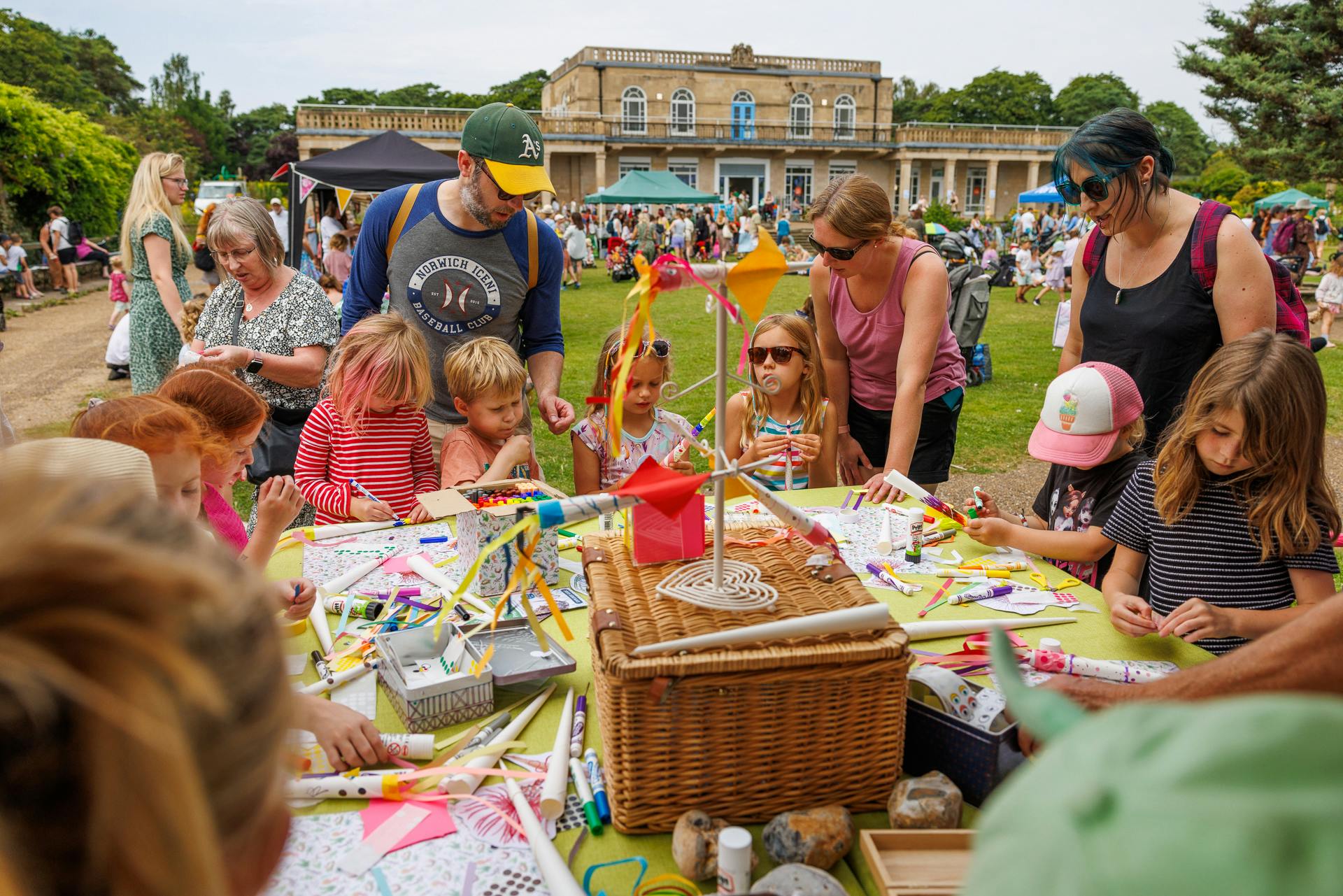 Children and families gathered around a table outside with craft activities