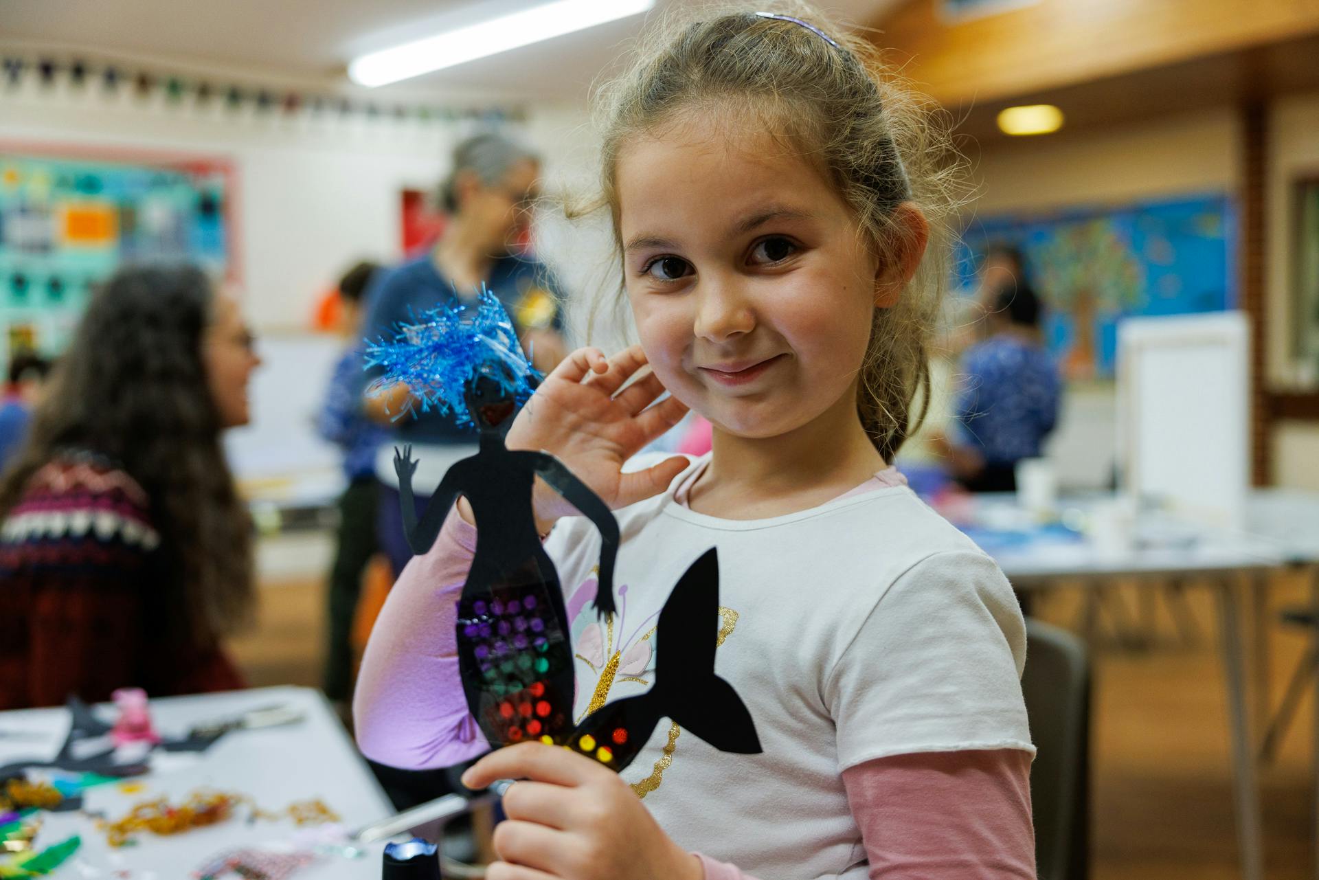 A child holds up their mermaid shadow puppet.