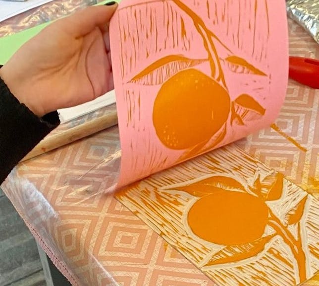 Hands peeling linocut print from block
