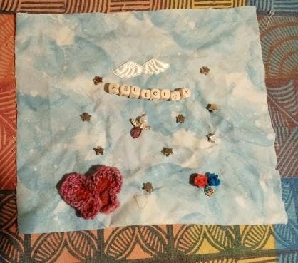 A blue and white piece of fabric with beading and appliques, with the name 