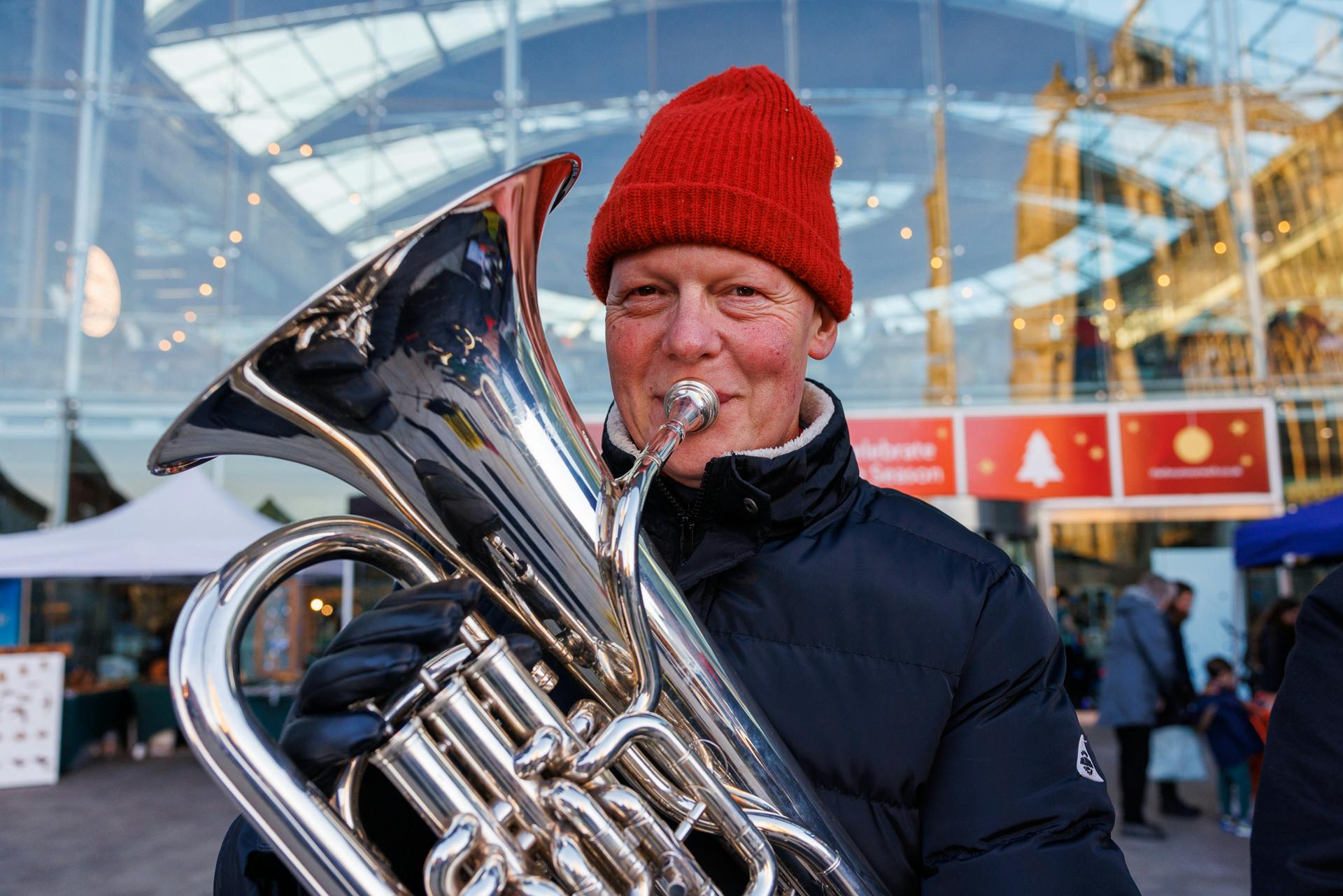 A man in a red hat blowing a brass intrument