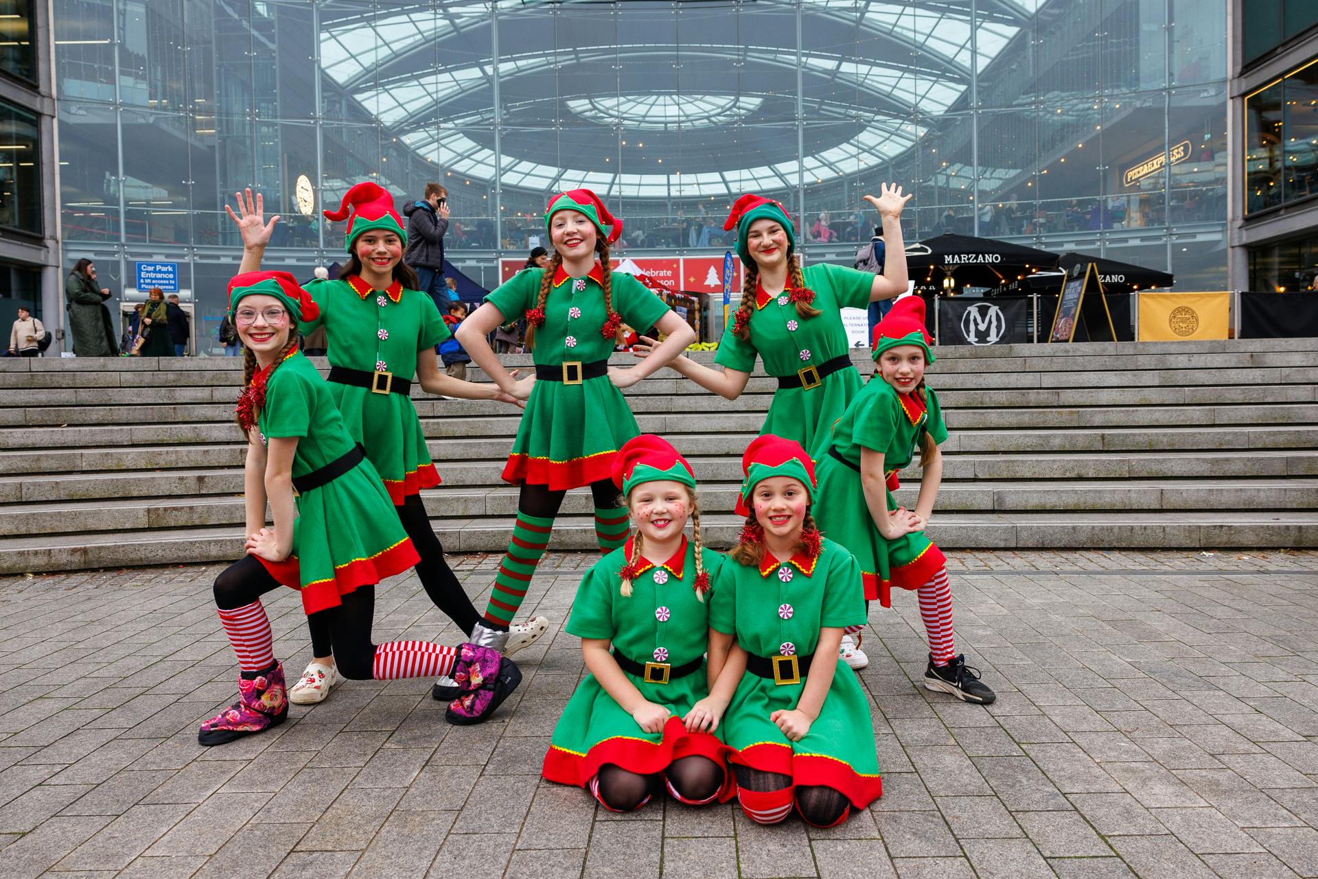 A group of girls dressed as Christmas elves in front of The Forum